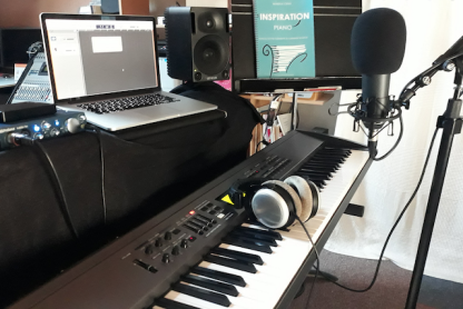 Clavier numérique avec un casque posé sur les touches, un micro professionnel sur pied et un ordinateur portable allumé. À l’arrière-plan, la couverture du livre “Inspiration Piano” de Marina Graf est posée en évidence.